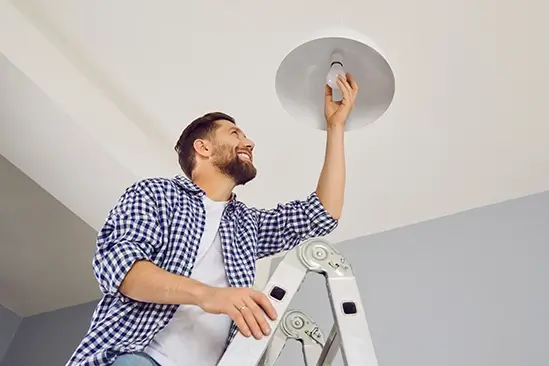 A man putting in a lightbulb on a cieling fixture