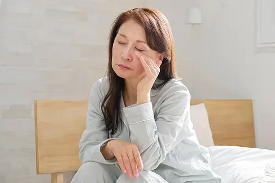A woman rising from her bed and looking tired