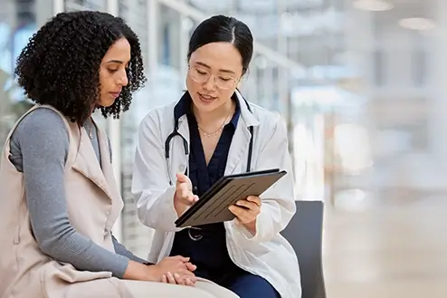 A doctor showing a patient a clipboard and discussing