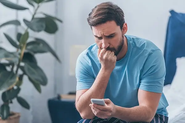 A man looking at his phone worriedly