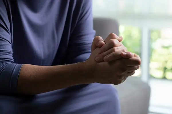 A person sitting with their hands clasped