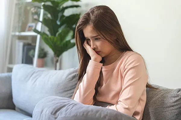 A woman sitting at a couch looking concerned
