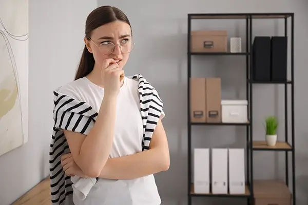 A woman biting her nail and looking worried