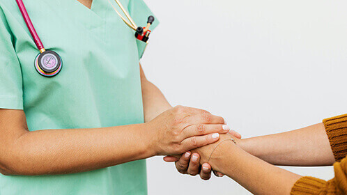 A doctor and a patient holding hands.
